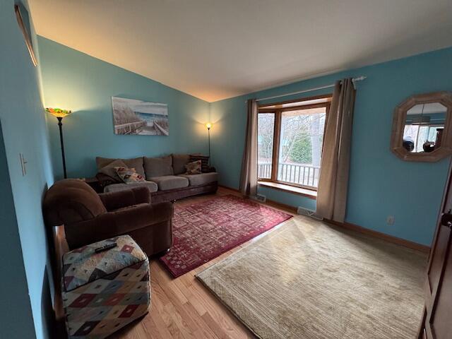 living room with vaulted ceiling and light wood-type flooring