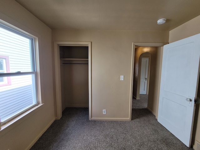 unfurnished bedroom featuring a closet and dark colored carpet