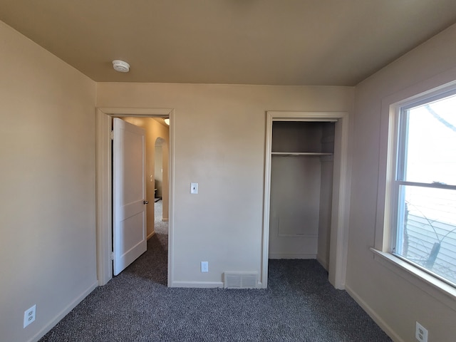 unfurnished bedroom with a closet and dark colored carpet