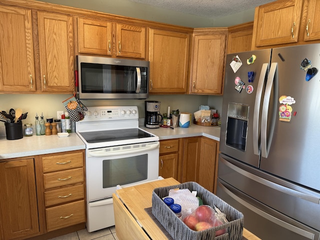 kitchen featuring appliances with stainless steel finishes, light tile patterned floors, and a textured ceiling