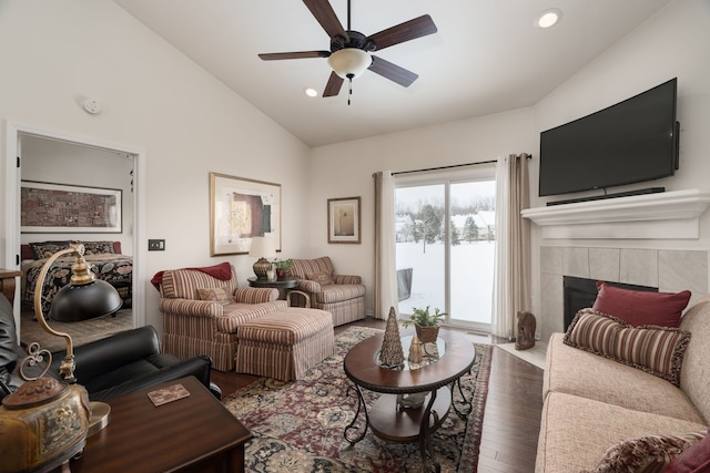 living room with ceiling fan, vaulted ceiling, a fireplace, and wood-type flooring