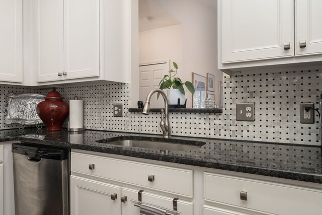 kitchen featuring sink, dishwasher, white cabinetry, backsplash, and dark stone countertops