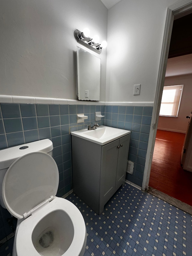 bathroom featuring vanity, tile walls, and toilet