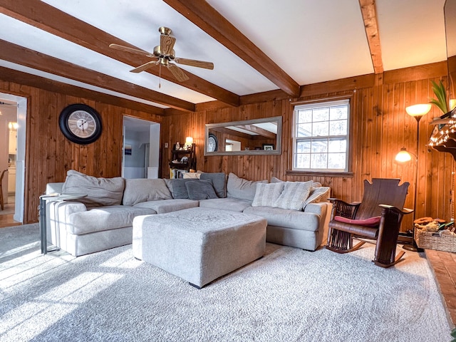 living room featuring ceiling fan, beamed ceiling, and wooden walls