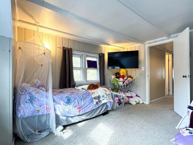 carpeted bedroom with beamed ceiling and wood walls