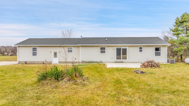 rear view of property featuring a lawn and central air condition unit