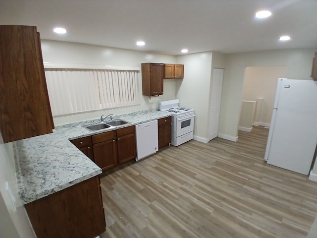 kitchen with light stone counters, white appliances, light hardwood / wood-style floors, and sink