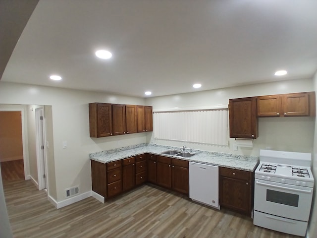 kitchen with light stone counters, white appliances, light hardwood / wood-style floors, and sink