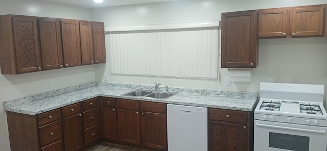 kitchen featuring light stone counters, white appliances, and sink