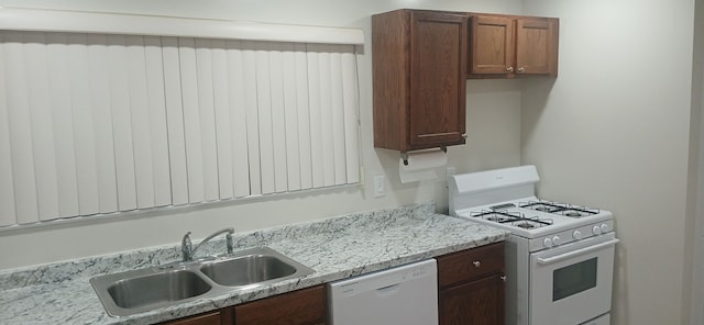 kitchen with sink, light stone counters, and white appliances