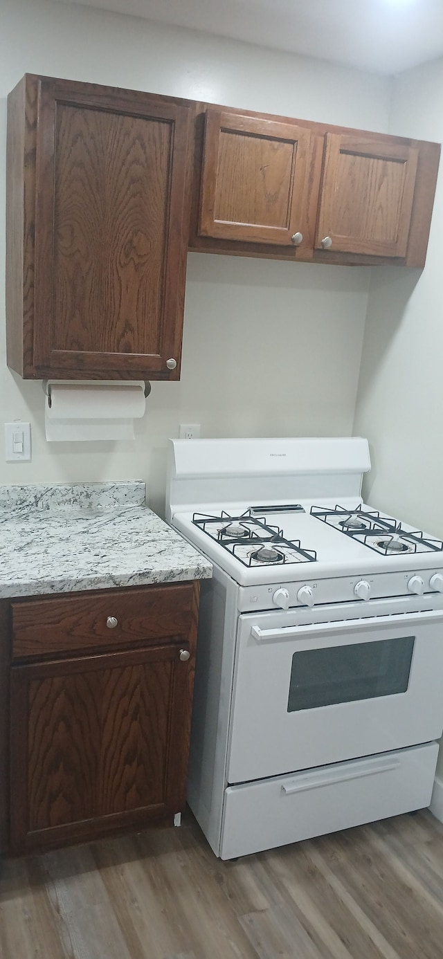 kitchen with light stone countertops, dark wood-type flooring, and white range with gas stovetop