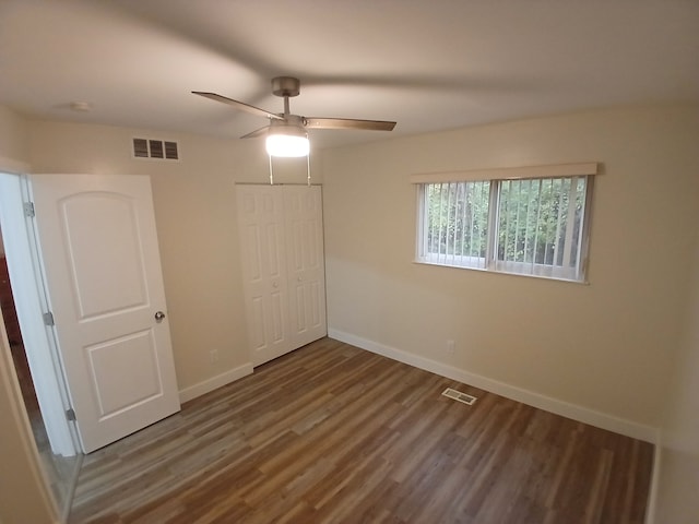 unfurnished bedroom with a closet, dark hardwood / wood-style floors, and ceiling fan