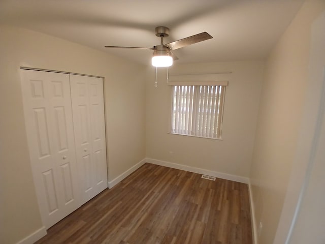 unfurnished bedroom with ceiling fan, dark hardwood / wood-style flooring, and a closet