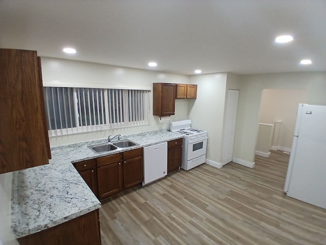 kitchen featuring light stone countertops, sink, white appliances, and light wood-type flooring