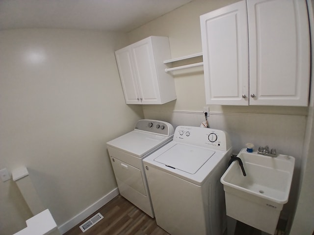 washroom featuring sink, dark wood-type flooring, washer and clothes dryer, and cabinets