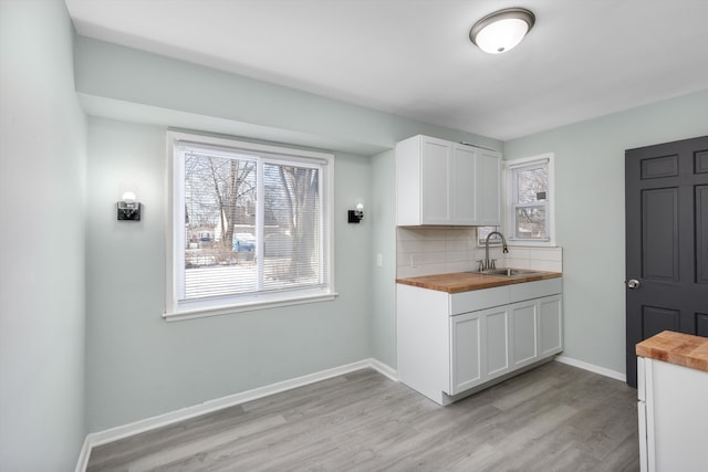 kitchen with sink, decorative backsplash, wooden counters, and white cabinets