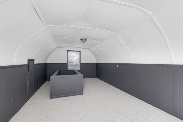 interior space with vaulted ceiling and light carpet