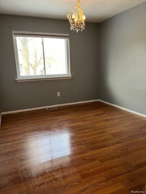392 Hillcrest Dr, Saline, MI 48176 - spare room featuring healthy amount of natural light, a chandelier, and wood finished floors