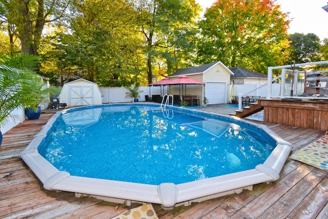 view of swimming pool with a wooden deck, a storage shed, and a garage