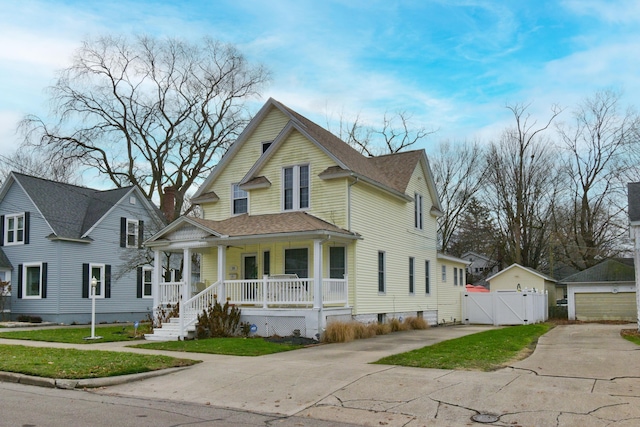 view of front of house featuring a garage, an outdoor structure, covered porch, and a front lawn