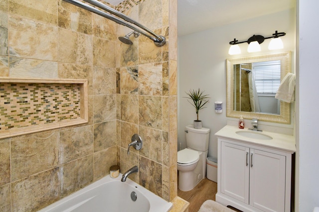 full bathroom featuring vanity, hardwood / wood-style floors, tiled shower / bath combo, and toilet