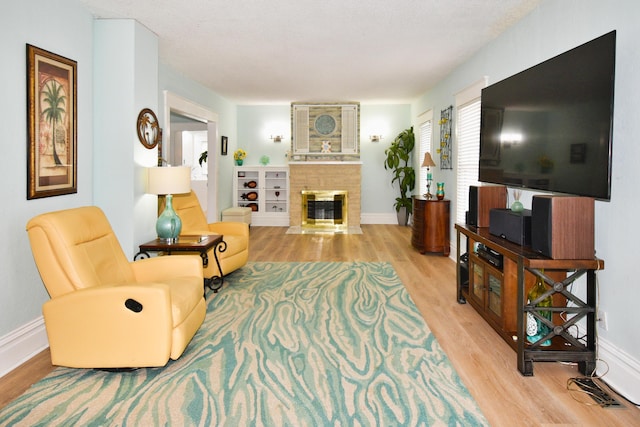 living room featuring a fireplace, light hardwood / wood-style flooring, and a textured ceiling