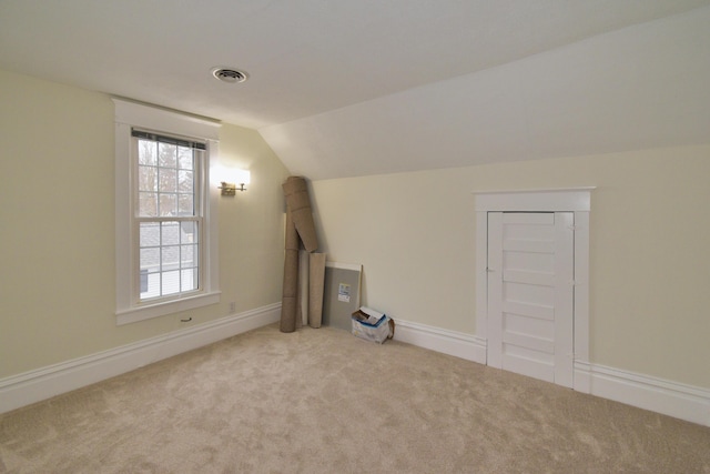 bonus room with light colored carpet and vaulted ceiling