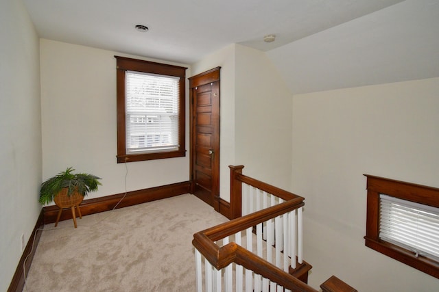 hallway with light colored carpet and vaulted ceiling