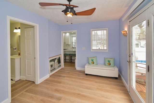 living area featuring ceiling fan, light hardwood / wood-style floors, and a textured ceiling