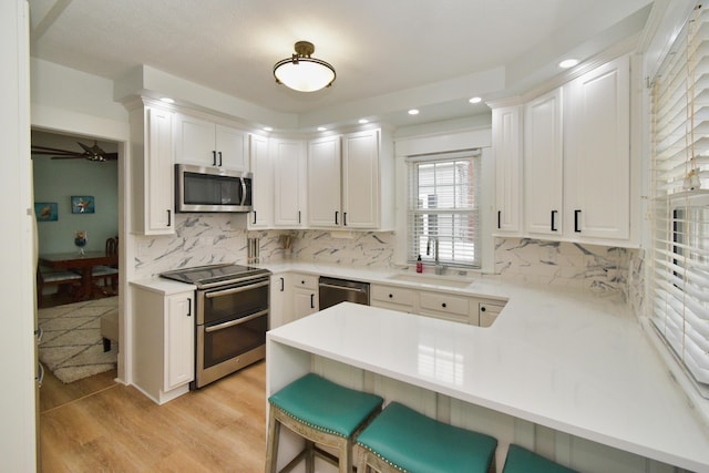 kitchen featuring white cabinetry, sink, kitchen peninsula, and appliances with stainless steel finishes