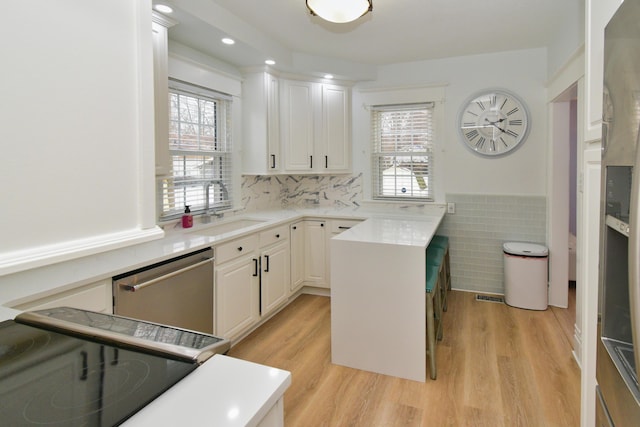 kitchen featuring white cabinetry, sink, a center island, stainless steel dishwasher, and light hardwood / wood-style floors