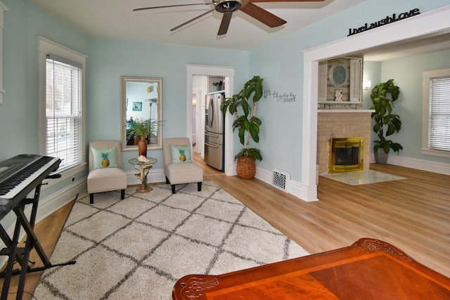 sitting room with hardwood / wood-style flooring, a tile fireplace, and ceiling fan