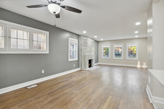 unfurnished living room with hardwood / wood-style flooring, ceiling fan, and a high end fireplace