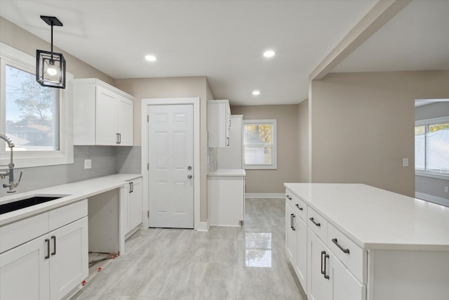 kitchen with pendant lighting, tasteful backsplash, sink, white cabinets, and a center island