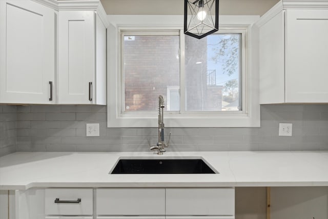 kitchen with tasteful backsplash, light stone countertops, sink, and white cabinets