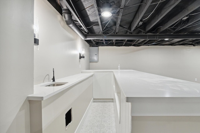 bar with light stone counters, electric panel, and sink