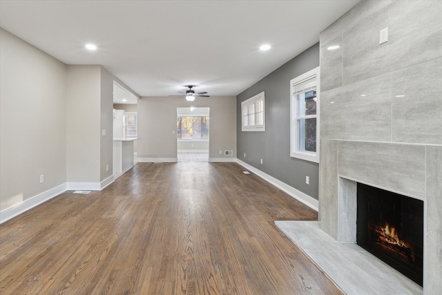 unfurnished living room with wood-type flooring, ceiling fan, and a fireplace