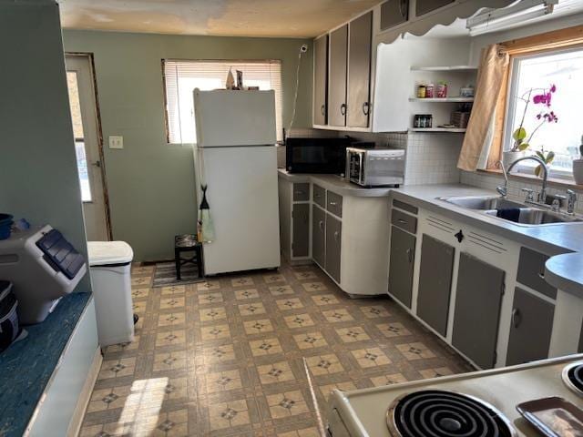 kitchen featuring white refrigerator, a healthy amount of sunlight, sink, and tasteful backsplash