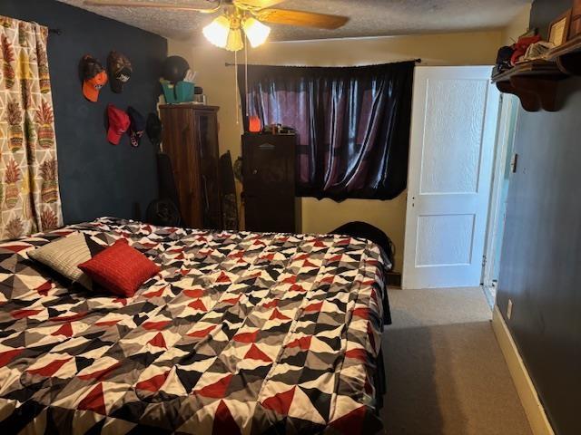 bedroom with ceiling fan, carpet, and a textured ceiling