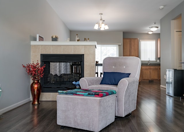 living room with dark wood-type flooring, a fireplace, sink, and a notable chandelier