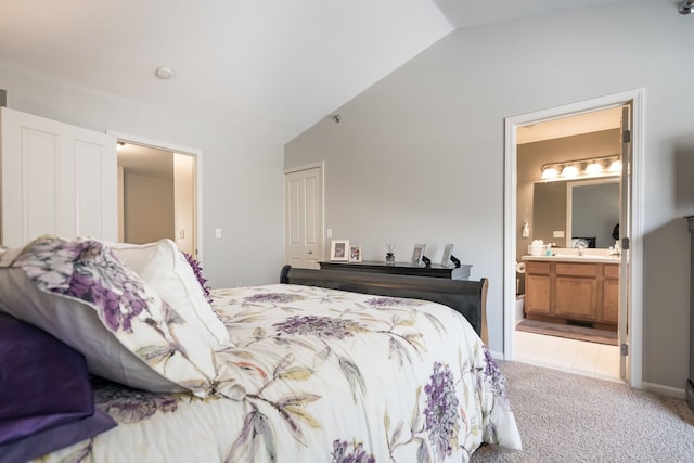 bedroom with lofted ceiling, sink, ensuite bath, light carpet, and a closet