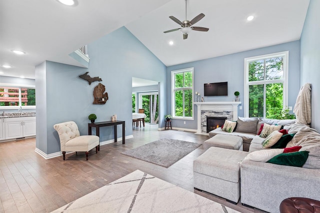 living room featuring ceiling fan, high vaulted ceiling, sink, and light hardwood / wood-style floors