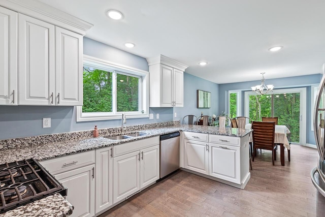 kitchen featuring pendant lighting, white cabinetry, sink, stainless steel dishwasher, and kitchen peninsula