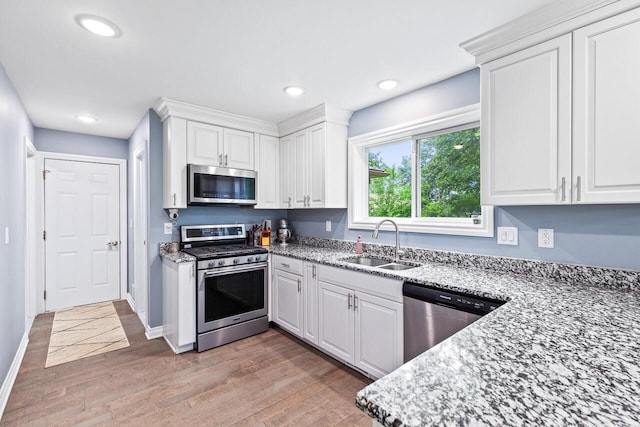 kitchen with white cabinetry, appliances with stainless steel finishes, sink, and light stone counters