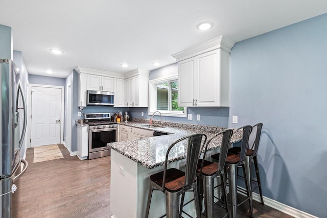 kitchen featuring white cabinetry, stainless steel appliances, kitchen peninsula, and sink