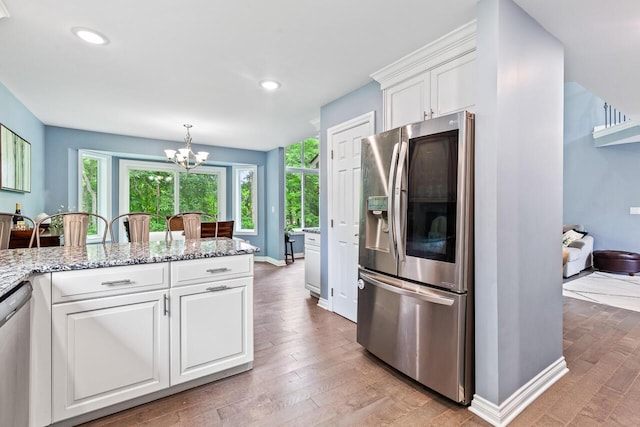 kitchen with white cabinetry, stainless steel appliances, light stone counters, and pendant lighting