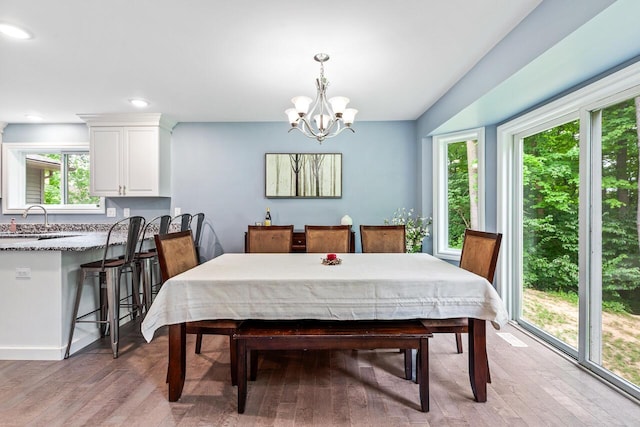 dining area with sink, light hardwood / wood-style floors, and a notable chandelier