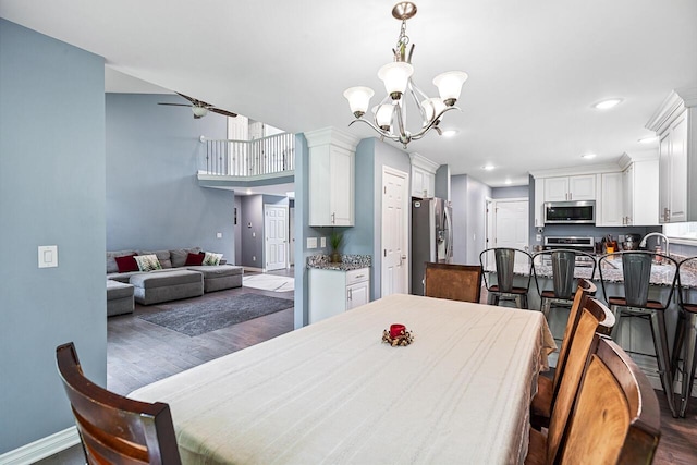 dining area featuring dark hardwood / wood-style flooring and ceiling fan with notable chandelier