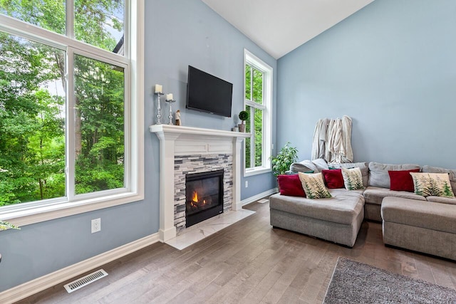 living room featuring vaulted ceiling, hardwood / wood-style floors, and a fireplace