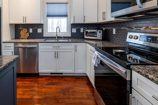 kitchen with dark stone countertops, stainless steel appliances, sink, and white cabinets